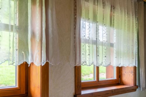 two windows with white curtains in a room at Salaš Syrex in Zázrivá