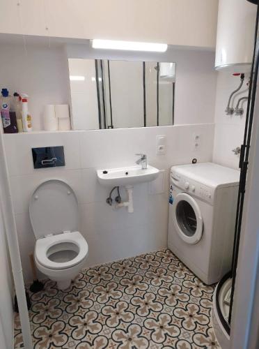 a bathroom with a toilet and a washing machine at Apartament przy basenie in Giżycko