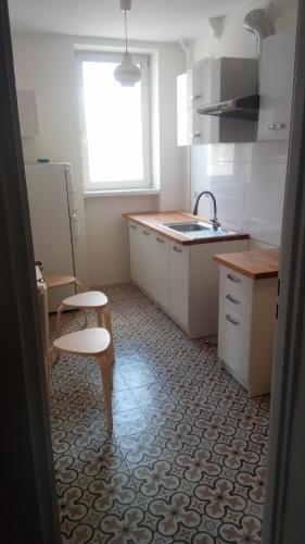 a kitchen with a sink and a table and a stool at Apartament przy basenie in Giżycko