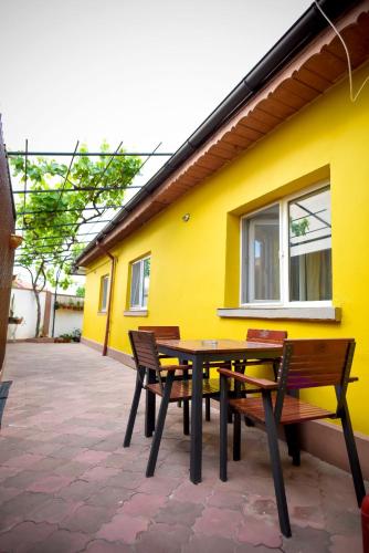a table and benches in front of a yellow building at Casa Lili in Mangalia