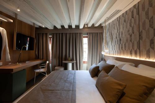 ヴェネツィアにあるPalazzo Piancaの大きなベッドとデスクが備わるホテルルームです。