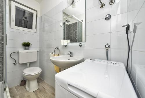 a white bathroom with a toilet and a sink at Apartments Marsela in Tučepi