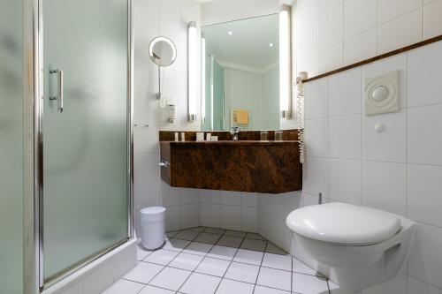 a bathroom with a toilet, sink, and shower stall at Schlosspark Hotel in Berlin
