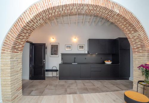 an archway leads into a kitchen with black cabinets at Casa Miguel - Apartamento 5 in Sanlúcar de Barrameda