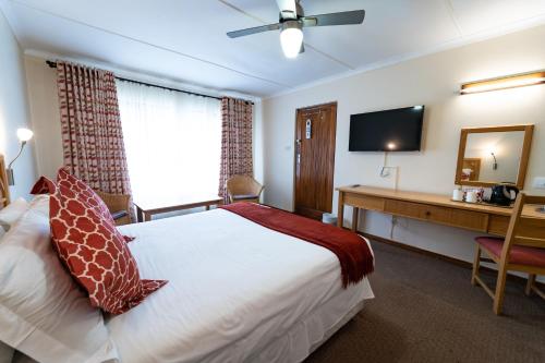 a bedroom with a bed and a desk and a television at Gooderson Drakensberg Gardens Golf & Spa Resort in Drakensberg Garden