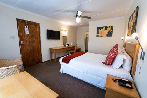 a hotel room with a bed and a desk at Gooderson Drakensberg Gardens Golf & Spa Resort in Drakensberg Garden