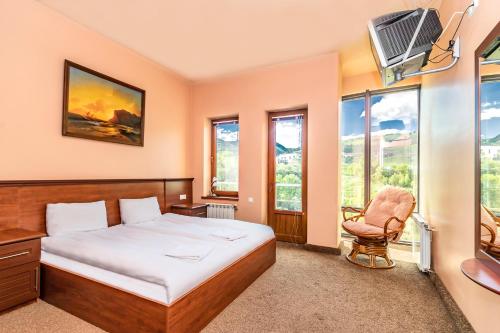 a bedroom with a bed and a chair and windows at Tsaghkadzor Homeland in Tsaghkadzor