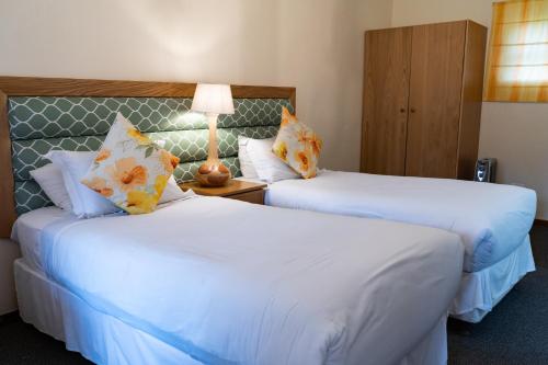 a hotel room with two beds and a lamp at Gooderson Drakensberg Gardens Golf & Spa Resort in Drakensberg Garden