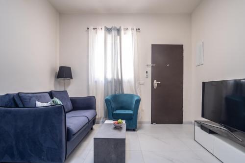 sala de estar con sofá azul y TV en PORT CITY HAIFA - Luxury Apartments 50 mtrs From The Beach, en Haifa