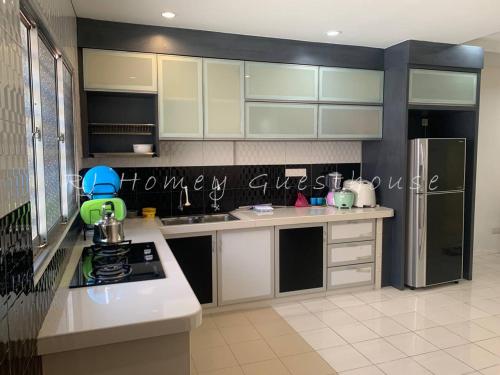 a kitchen with white cabinets and a refrigerator at RJ Homey Guesthouse in Sungai Petani