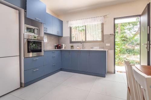 a kitchen with blue cabinets and a white tile floor at PORT CITY HAIFA - Luxury Apartments 50 mtrs From The Beach in Haifa