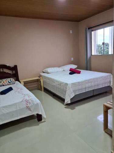 a bedroom with two beds and a window at Pássaros do Cerrado Suítes in Alto Paraíso de Goiás