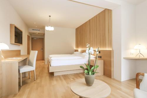 a bedroom with a bed and a desk and a table at Hotel Spitaler in Appiano sulla Strada del Vino