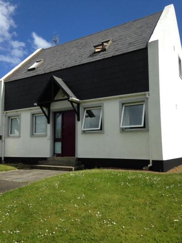 a white and black house with a red door at Detached two bedroom cottage in Riverchapel