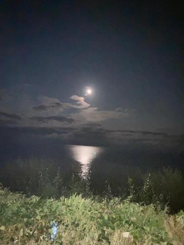 a full moon over a body of water at night at Detached two bedroom cottage in Riverchapel