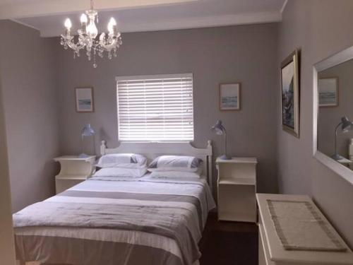 a bedroom with a large bed and a chandelier at Meerhuis Cottage in Langebaan