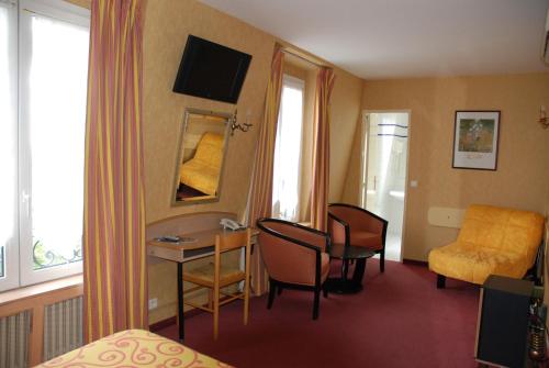 a hotel room with a bed and a table and chairs at Hôtel Transcontinental in Paris