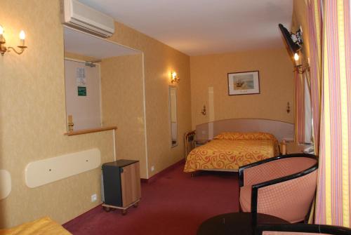 a hotel room with a bed and a table and chairs at Hôtel Transcontinental in Paris