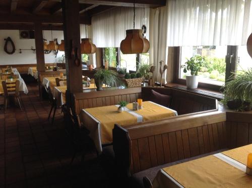 a dining room with tables and chairs and windows at Landgasthof zum Wiesengrund in Hünfeld