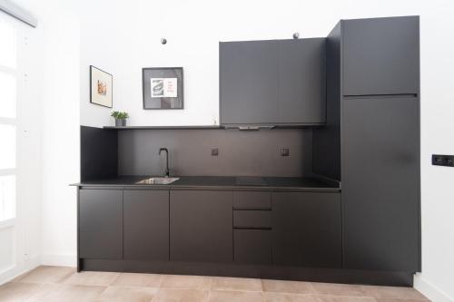 a black kitchen with a sink and a refrigerator at Casa Miguel - Apartamento 6 in Sanlúcar de Barrameda