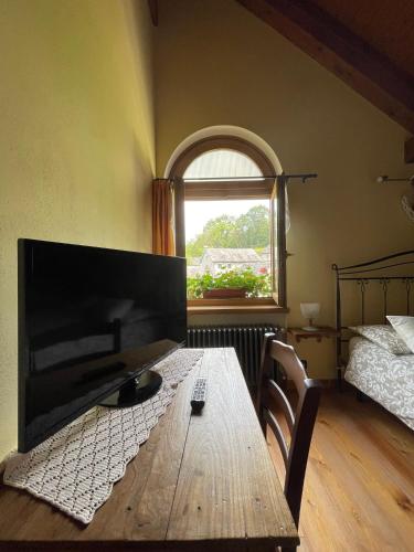 a room with a wooden table and a bed and a window at Casa Brencio in Masera