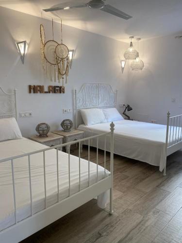 two beds in a bedroom with white walls at AlquilaEasy Windsor in Benalmádena