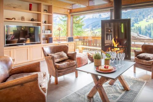 a living room with a fireplace and a table and chairs at Chalet Musini - OVO Network in Le Grand-Bornand