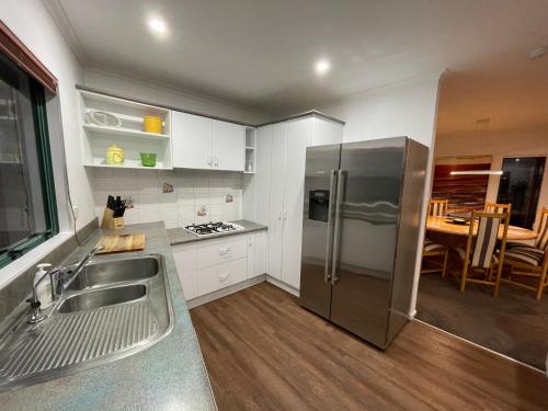 a kitchen with a stainless steel refrigerator and a table at Luxury Home Next to Ocean and Walkway in New Plymouth