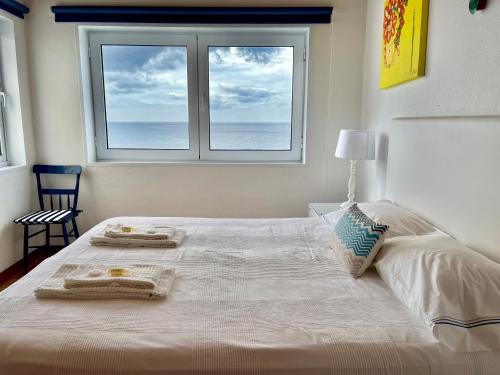 um quarto com uma grande cama branca e uma janela em Casa do Mar em São Roque
