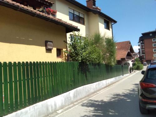 a green fence in front of a house at Guest House Isidora in Arilje