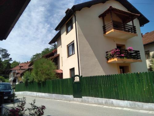 a house with a green fence and a building at Guest House Isidora in Arilje