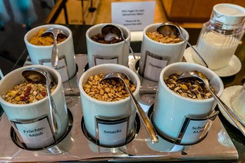 a group of bowls of food on a tray with spoons at Schlosspark Hotel in Berlin