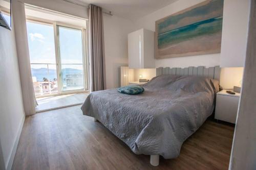 1 dormitorio con cama y ventana grande en Très beau T2 climatisé refait à neuf, vue mer panoramique exceptionnelle à 120m à pied de la plage, en La Ciotat