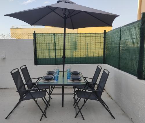 a table with chairs and an umbrella on a patio at La Casita Blanca in El Astillero