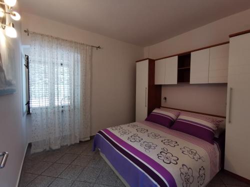 a bedroom with a bed with purple sheets and a window at More in Malinska