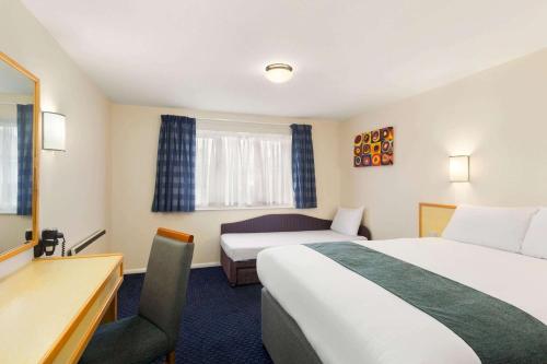 Habitación de hotel con 2 camas y escritorio en Days Inn Sutton Scotney South, en Sutton Scotney