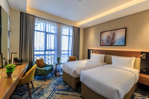 a hotel room with two beds and a desk at S19 Hotel-Al Jaddaf Metro Station in Dubai