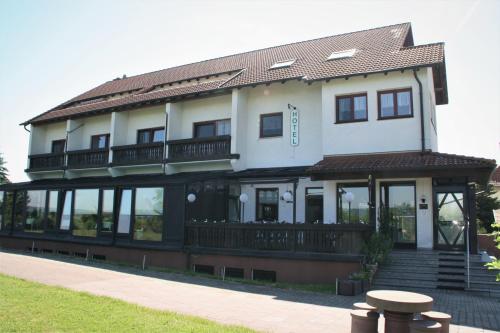 a large white house with a balcony and a table at Hotel Waldschlösschen in Dankmarshausen