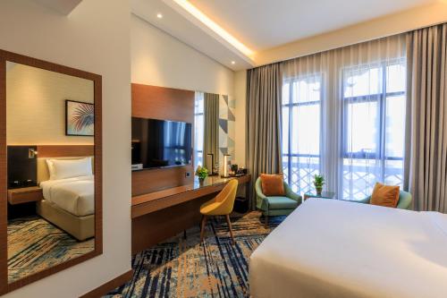 a hotel room with a bed and a desk and a mirror at S19 Hotel-Al Jaddaf Metro Station in Dubai