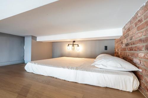 une chambre avec un lit avec un mur de briques dans l'établissement 10 SEGURANE - Magnifique Studio Mezzanine - Port de Nice, à Nice