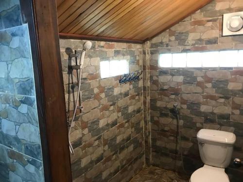 La salle de bains est pourvue de toilettes et d'un mur en pierre. dans l'établissement Gibbon Lodge, à Saen Monourom