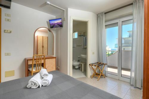 a bedroom with a bed and a mirror and a bathroom at Hotel Villa Lina in Riccione