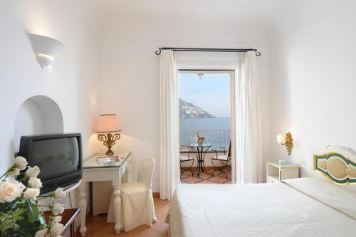 a bedroom with a bed and a desk and a television at Covo Dei Saraceni in Positano