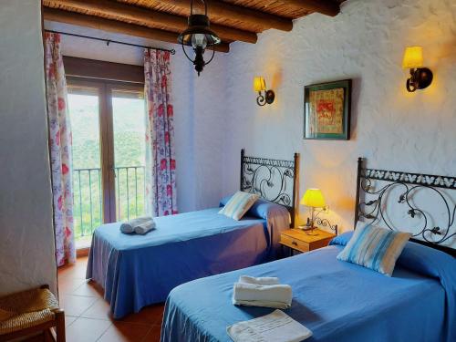 カニージャス・デ・アルバイダにあるVilla La Posadaのベッドルーム1室(青いシーツと窓付きのベッド2台付)