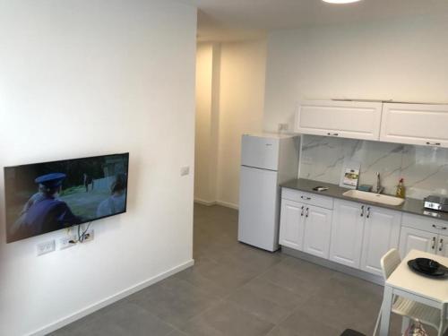 a kitchen with white cabinets and a tv on the wall at Isramax low-cost apartment near the sea. in Bat Yam