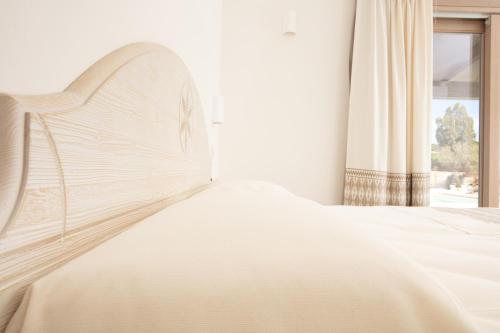 a white bed in a room with a window at La Corte Di Pulicinu in Baja Sardinia