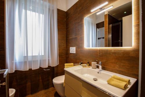 een badkamer met een wastafel, een toilet en een spiegel bij Casa Plauto in Bellaria-Igea Marina