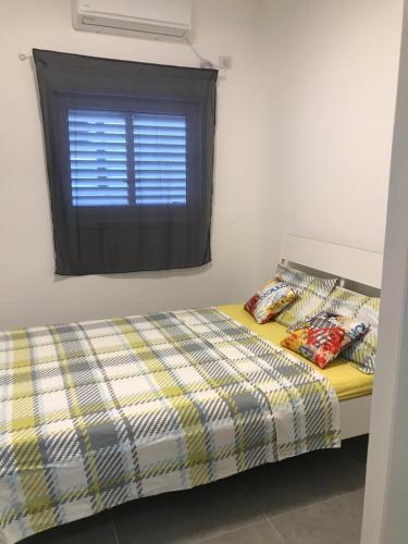 a bedroom with a bed and a window with pillows at Isramax low-cost apartment near the sea. in Bat Yam