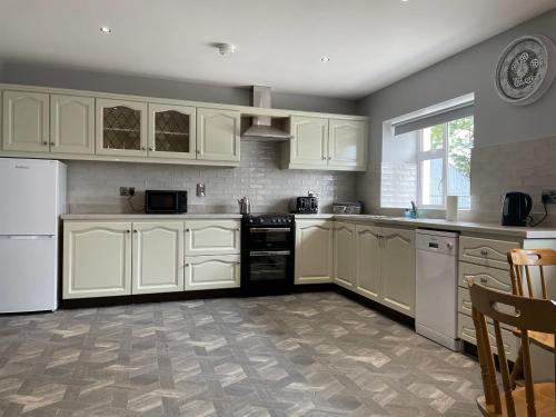 a kitchen with white cabinets and white appliances at Ketty's Cottage in Rosslea