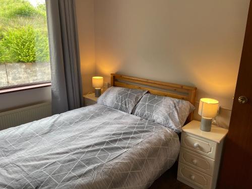 a bedroom with a bed and a window with two lamps at Ketty's Cottage in Rosslea